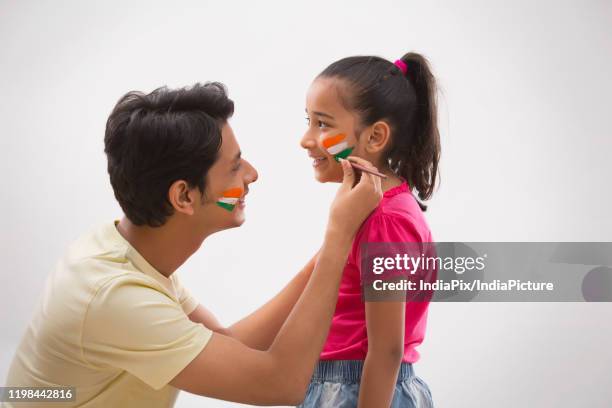 young man painting flag on a girls cheek, independence day - indian tricolor stock pictures, royalty-free photos & images