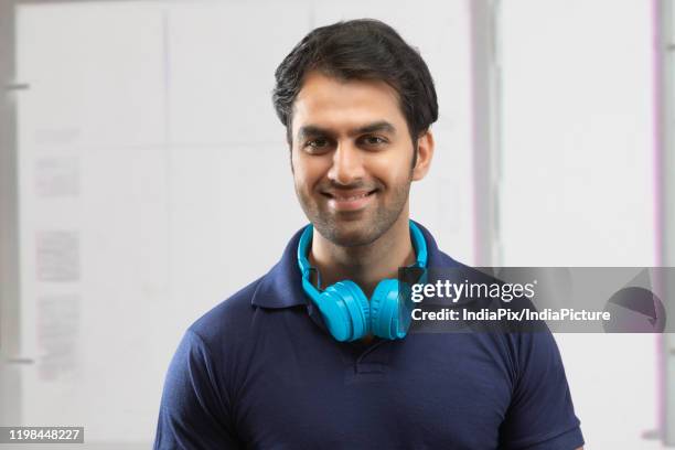 portrait of smiling man with headphones on neck - headphone man on neck stock pictures, royalty-free photos & images