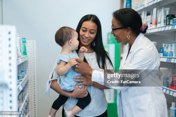 pharmacists talking with a young mother and her daughter stock photo - black pharmacist stock pictures, royalty-free photos & images
