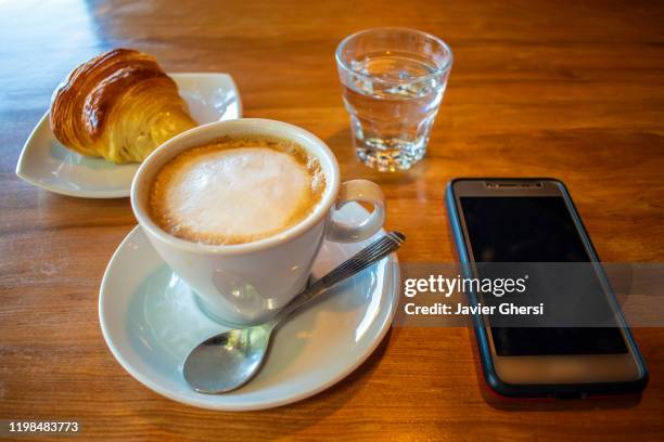 café con leche, medialuna de manteca y teléfono celular - teléfono stock pictures, royalty-free photos & images