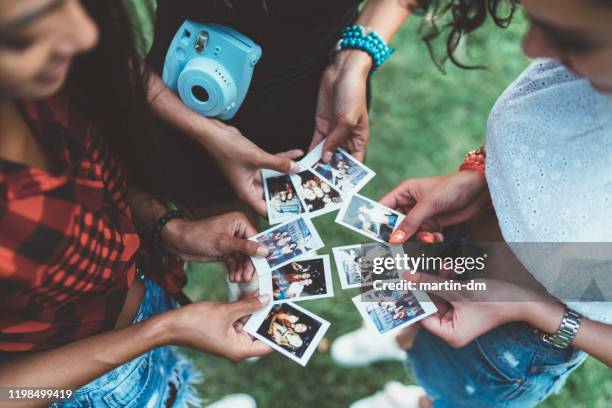 glückliche mädchen machen fotos mit sofortbildkamera - frauen mit fotoapparat stock-fotos und bilder