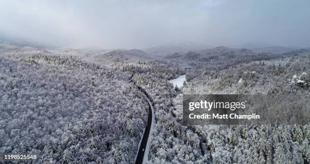 aerial of country road and snow covered trees in winter wilderness in adirondacks - adirondack state park stock pictures, royalty-free photos & images