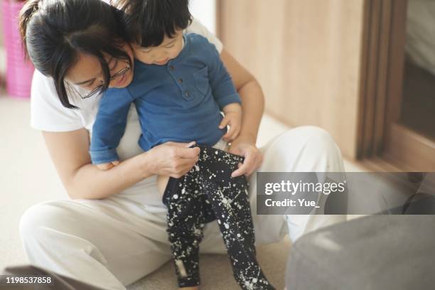 madre ayudando a bebé niño cambiarse de ropa - vestirse fotografías e imágenes de stock
