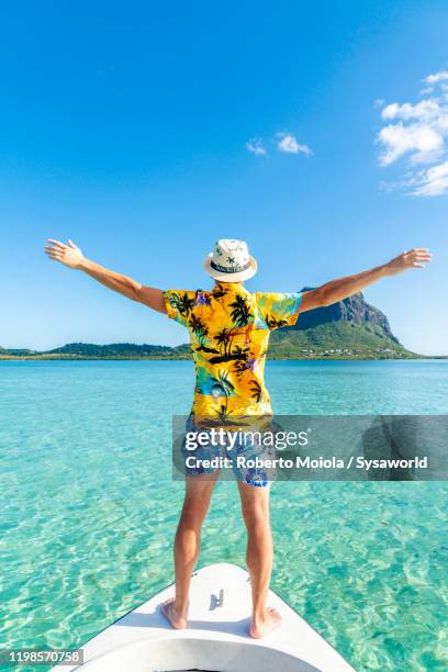 cheerful man with outstretched arms on boat trip, mauritius - isole mauritius stock pictures, royalty-free photos & images