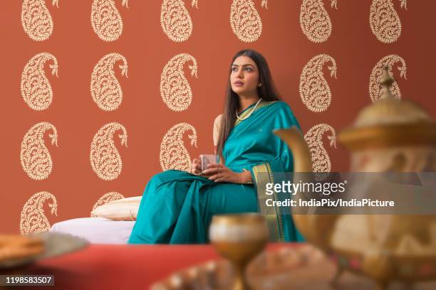 woman in saree having tea at home - indian royalty stock pictures, royalty-free photos & images