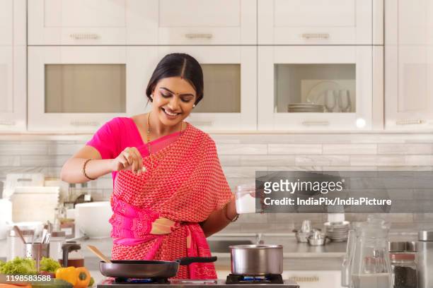 woman sprinkling salt in the dish - indian wife stock pictures, royalty-free photos & images