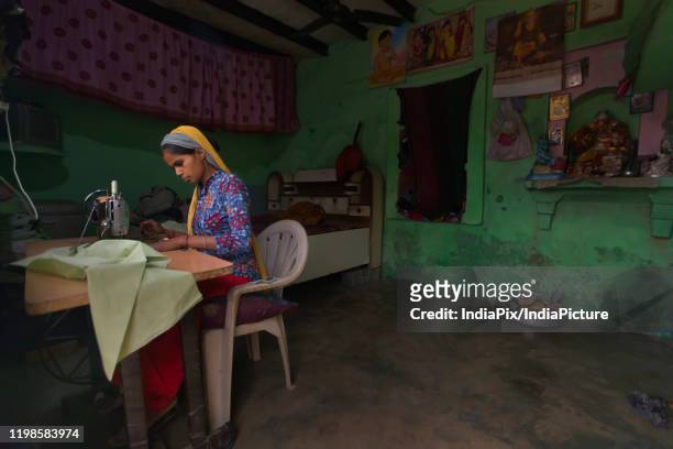 young girl stitching clothes in her hut - village asia stock-fotos und bilder