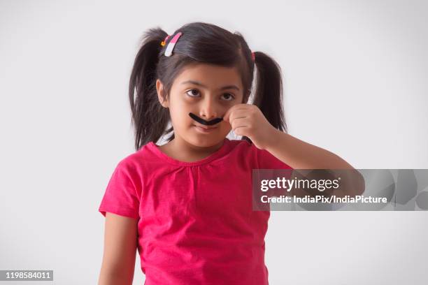 portrait of a young girl wearing fake moustache - fake of indian girls stock pictures, royalty-free photos & images