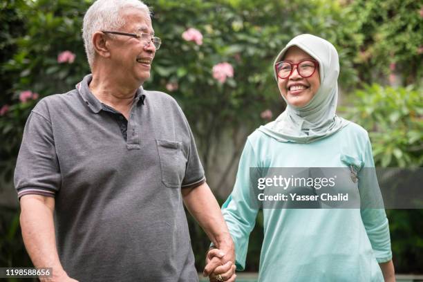 senior couple walking hand in hand - malay couple stock pictures, royalty-free photos & images