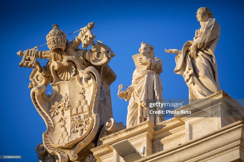 A detailed view of the statues above Bernini's colonnade in St. Peter's Basilica square at sunset