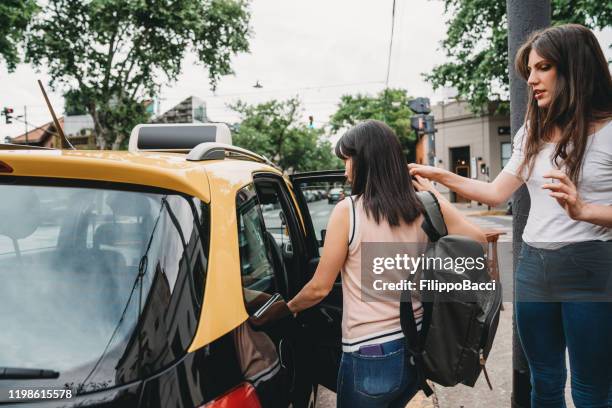 two young adult women getting in the cab - uber in buenos aires argentina stock pictures, royalty-free photos & images