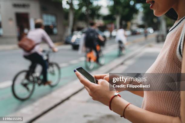 young adult woman using a mobile phone to call a taxi - uber in buenos aires argentina stock pictures, royalty-free photos & images