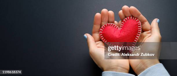 the girl is holding a red handmade heart on a black background. banner. - person holding up sign stock-fotos und bilder