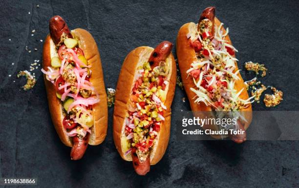 three gourmet hot dogs on black background - bbq sandwich foto e immagini stock