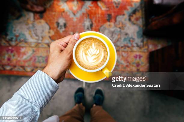 man holding yellow cup with cappuccino, personal perspective view - hand raised bildbanksfoton och bilder