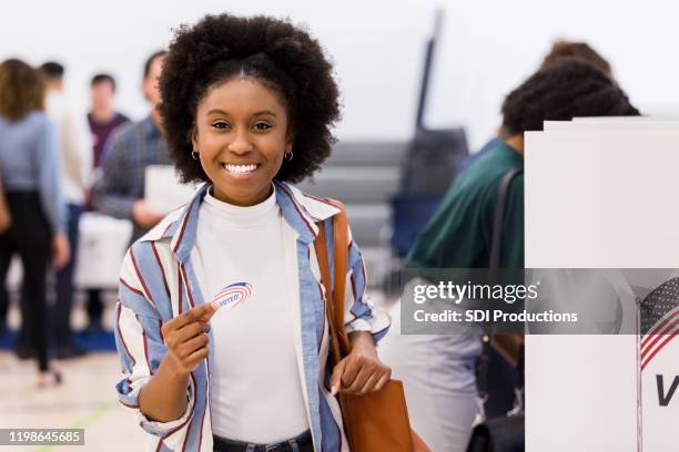 lachende jonge vrouw met "ik stem" sticker op de stemming plaats - young voters stockfoto's en -beelden