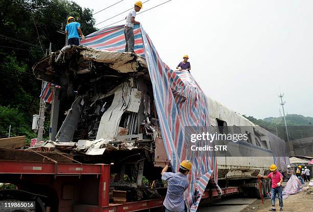 Damaged carriage involved in a fatal high-speed train collision is prepared for transport in the town of Shuangyu, on the outskirts of Wenzhou in the...