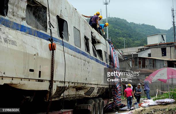 Workers prepare the wreckage of high-speed train carriage for transportation, two days after a fatal collision, in Shuangyu, on the outskirts of...