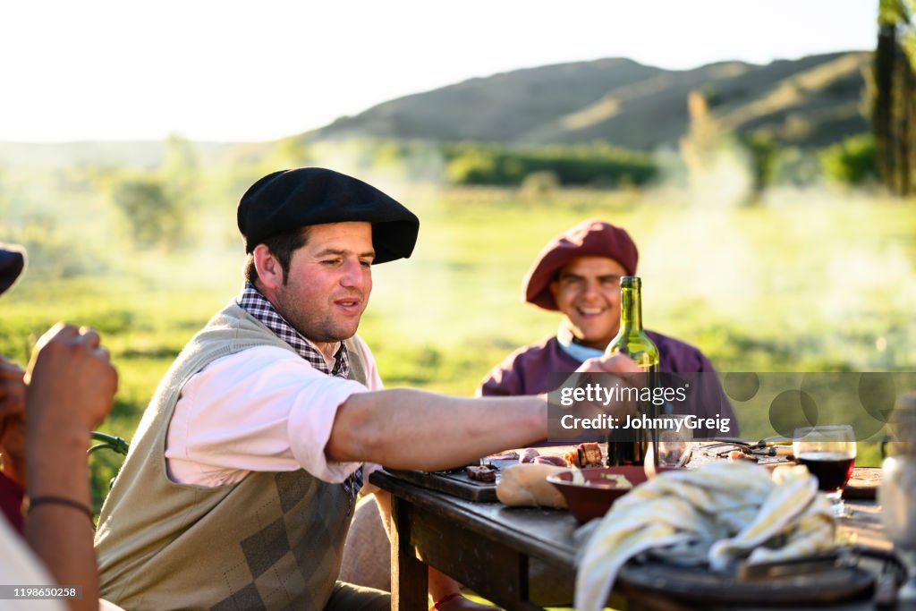 Argentine gauchos in traditional clothing enjoying asado