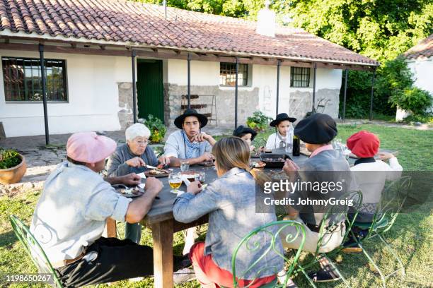 Three-generation Argentine gaucho family dining outdoors