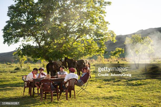 argentine teenage gauchos enjoying midday meal outdoors - argentina gaucho stock pictures, royalty-free photos & images