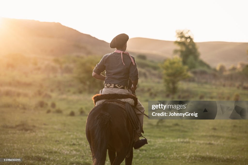 Junge Gaucho in traditioneller Kleidung Reiten am Nachmittag