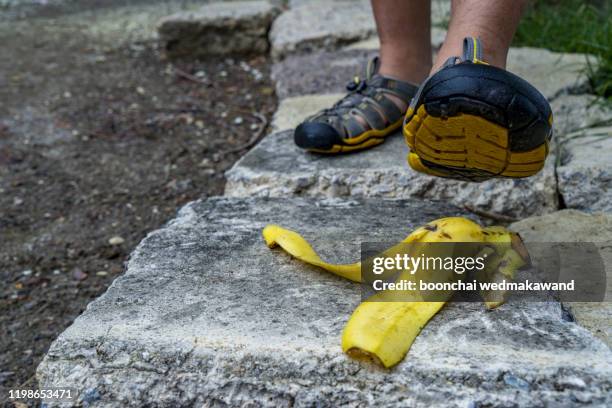 a banana skin lies on a walkway - injured street stockfoto's en -beelden