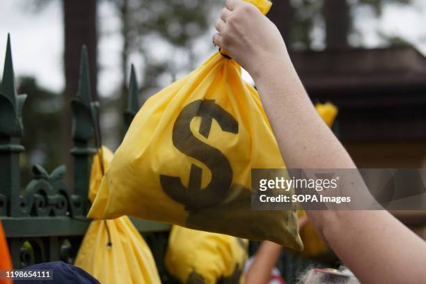 Hand of a protester holds a fake bag of money during the demonstration in Brisbane. Extinction Rebellion protesters vowed to disrupt the reopening of...