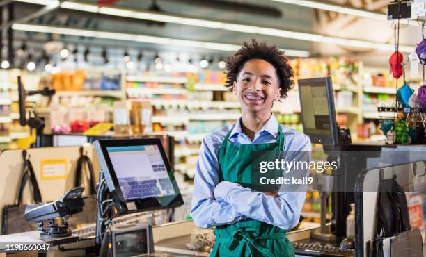 gemengde race tiener jongen werken als supermarkt kassier - shop till stockfoto's en -beelden