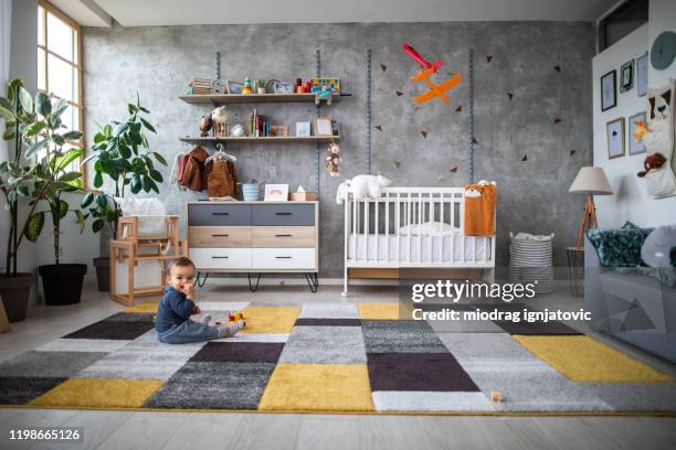 kleinkind junge liebe, wenn er allein mit seinen spielzeugen spielt - modern baby nursery stock-fotos und bilder