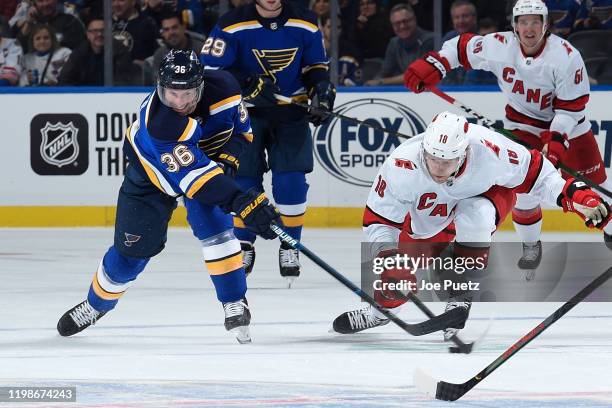 Troy Brouwer of the St. Louis Blues and Ryan Dzingel of the Carolina Hurricanes battle for the puck at Enterprise Center on February 4, 2020 in St....