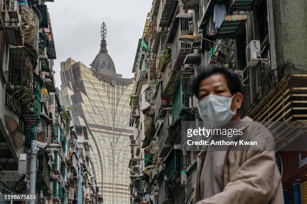 Man wearing protective mask walks across a street in front of the Grand Lisboa Hotel in a residential district on February 5, 2020 in Macau, China....