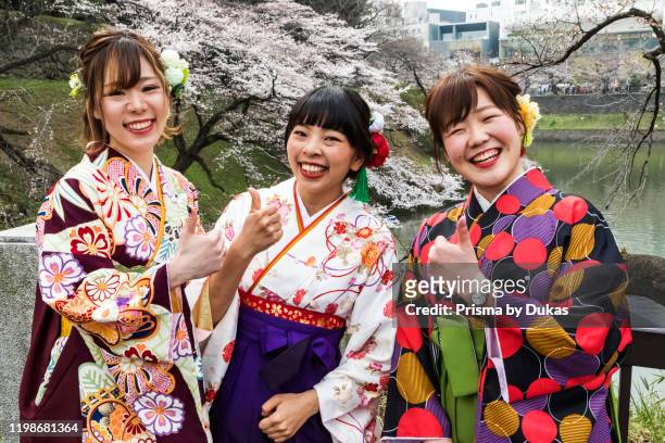Japan, Honshu, Tokyo, Kudanshita, Chidori-ga-fuchi, Female University Students Dressed in Traditional Hakama Graduation Costumes with Cherry Blossom...