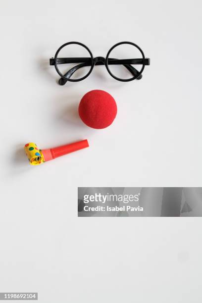 face made with glasses, red nose and party horn blower - clown stock-fotos und bilder