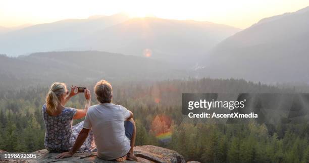 coppia matura rilassarsi su sporgenza di montagna, guardare fuori per vedere - pensionamento foto e immagini stock
