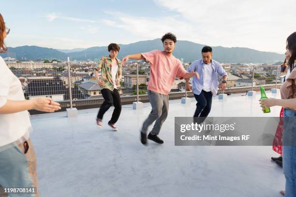 group of young japanese men and women dancing on a rooftop in an urban setting. - asian male dancer stock pictures, royalty-free photos & images