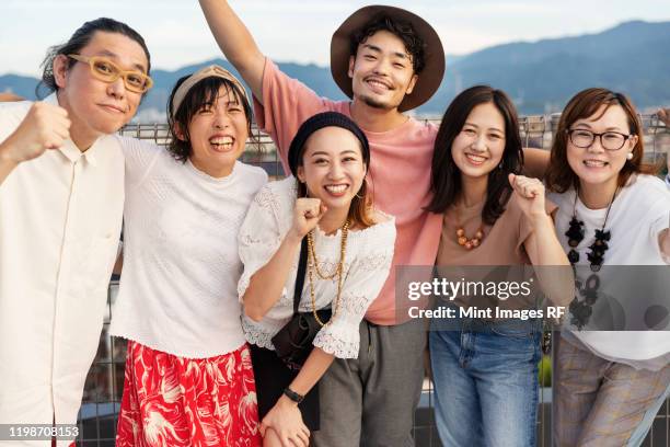 smiling group of young japanese men and women standing on a rooftop in an urban setting. - 日本人　女性　友達 ストックフォトと画像