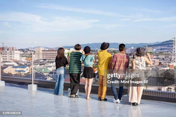 group of young japanese men and women standing on a rooftop in an urban setting. - fukuoka city photos et images de collection