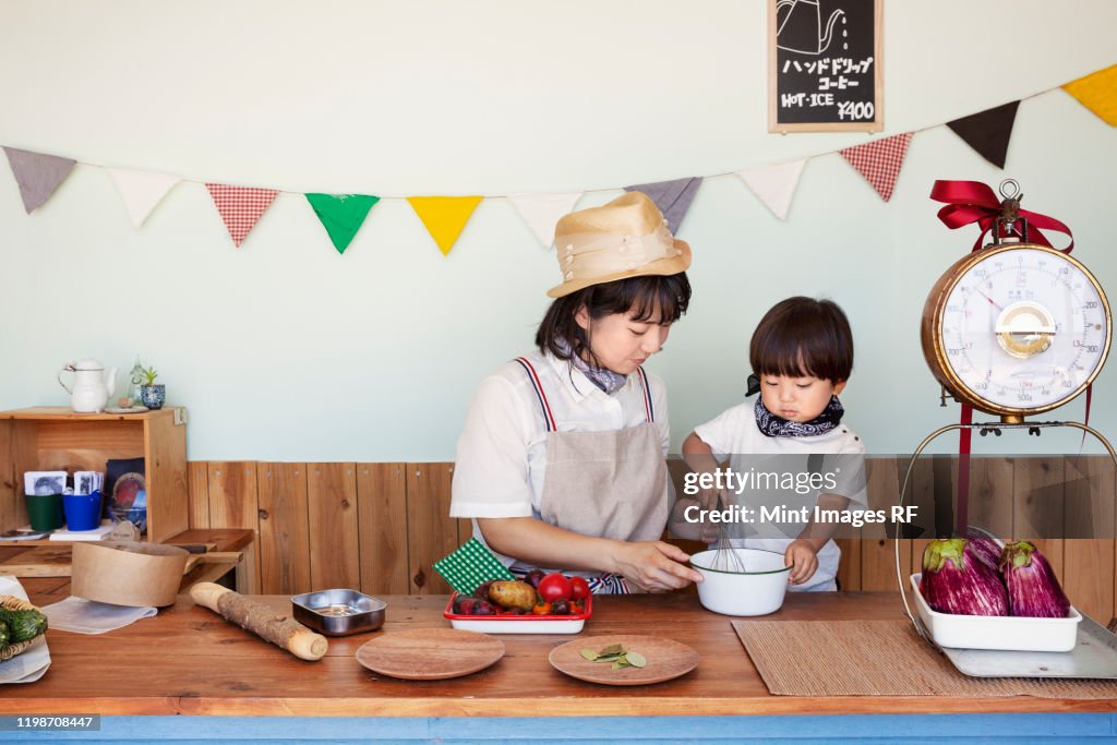 Japanese woman and boy standing in a farm shop, preparing food.