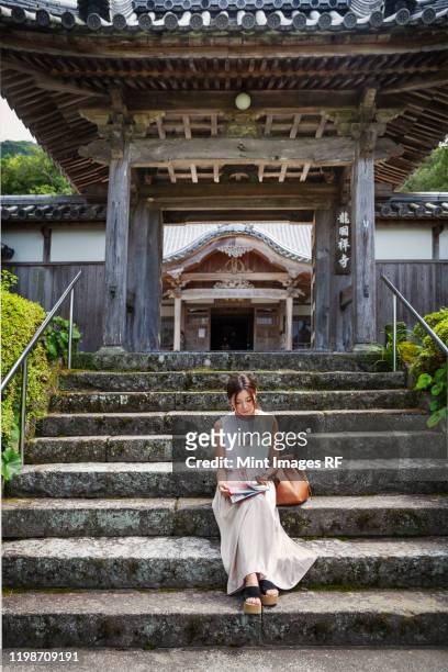 japanese woman sitting on steps outside a buddhist temple. - chinese temple imagens e fotografias de stock