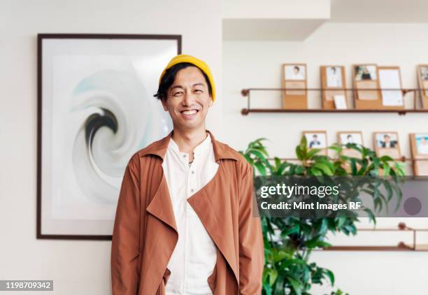 male japanese professional standing in a co-working space, smiling at camera. - creative rf stock-fotos und bilder