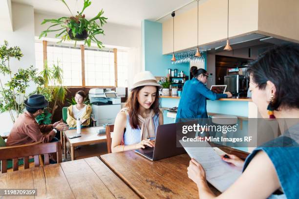 group of young japanese professionals working on laptop computers in a co-working space. - creative rf stockfoto's en -beelden