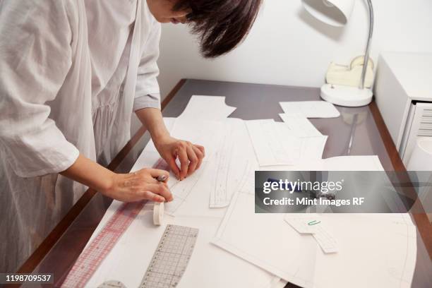 japanese woman wearing glasses working at a desk in a small fashion boutique. - creative rf stockfoto's en -beelden