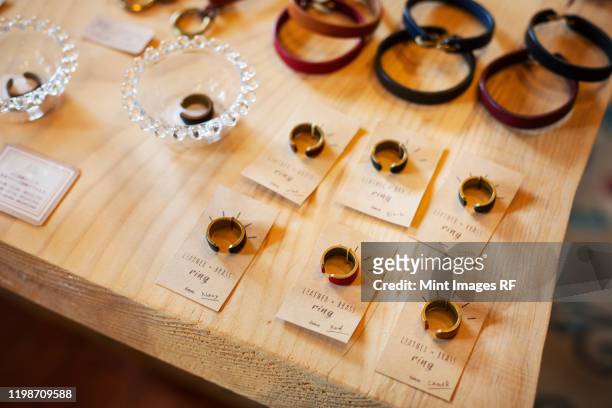 high angle close up of finger rings and leather bracelets on a table in a leather shop. - jewellery products stock pictures, royalty-free photos & images