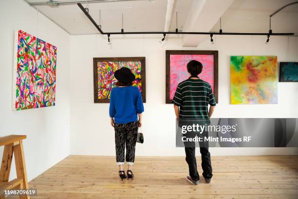 rear view of japanese man and woman looking at abstract painting in an art gallery. - art gallery people fotografías e imágenes de stock