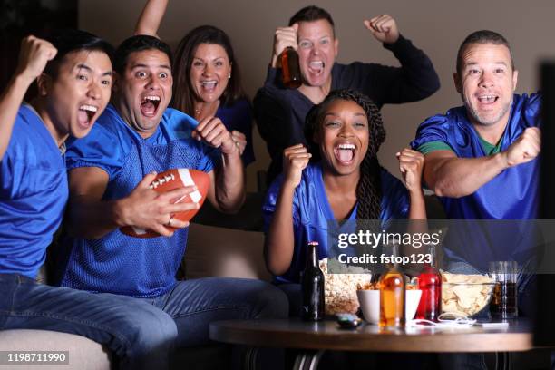 football fans watching the game at home on television. - football jersey stock pictures, royalty-free photos & images