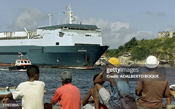 Havana residents watch as the Express container ship docks 16 December with 20 containers of frozen chicken, worth about 300,000 USD, shipped from...