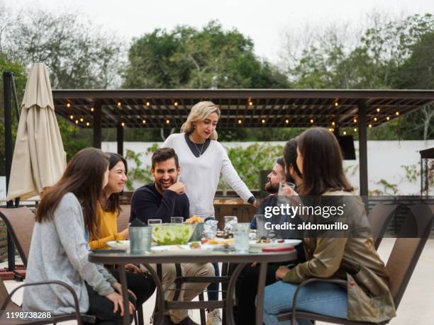 large group of joyful friends having fun while eating - large dinner party stock pictures, royalty-free photos & images