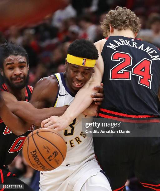 Aaron Holiday of the Indiana Pacers tries to move between Coby White and Lauri Markkanen of the Chicago Bulls at the United Center on January 10,...