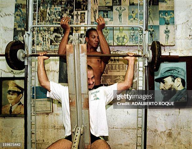 Ernesto Perdomo assists his fellow bodybuilder Javier Blanco during benching exercises 19 October 1999 in an improvised basement weight room in...